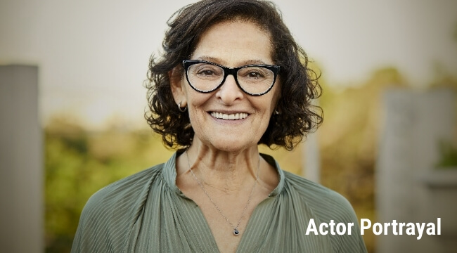 Older lady with glasses smiling. Actor portrayal